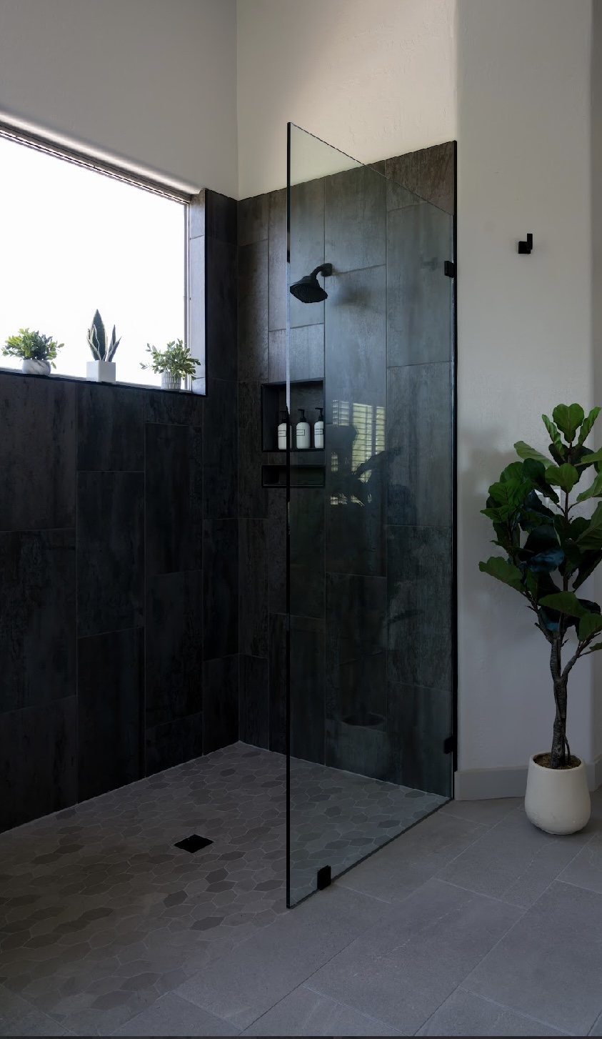 Finished walk-in shower with dark tile, glass panel and hexagonal floor tile in a Phoenix bathroom remodel