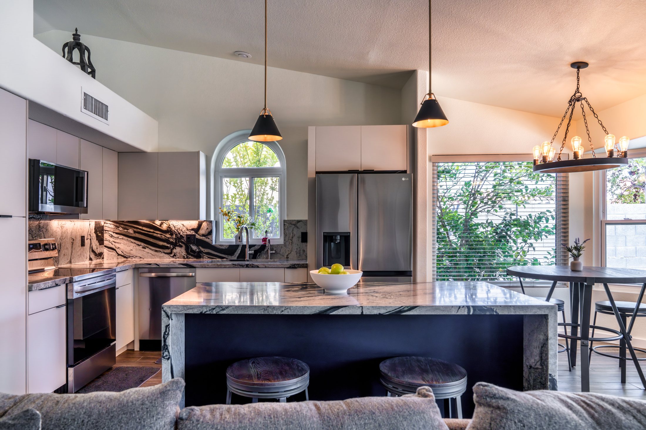 Phoenix kitchen remodel with book-matched stone backsplash, under-cabinet lighting and stainless appliances