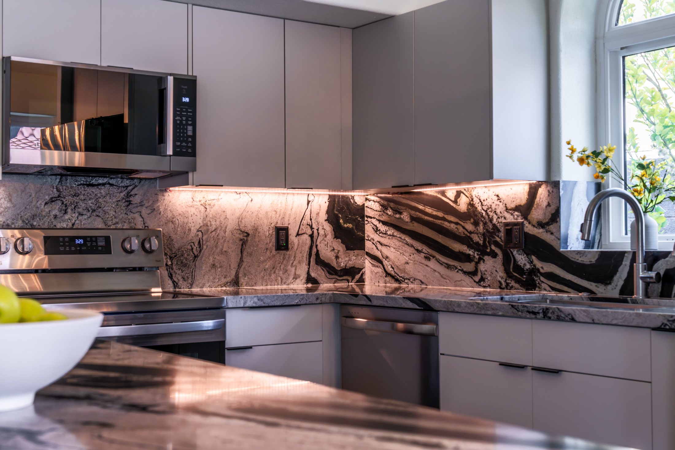 Waterfall stone island in a completed Phoenix kitchen remodel with pendant lighting
