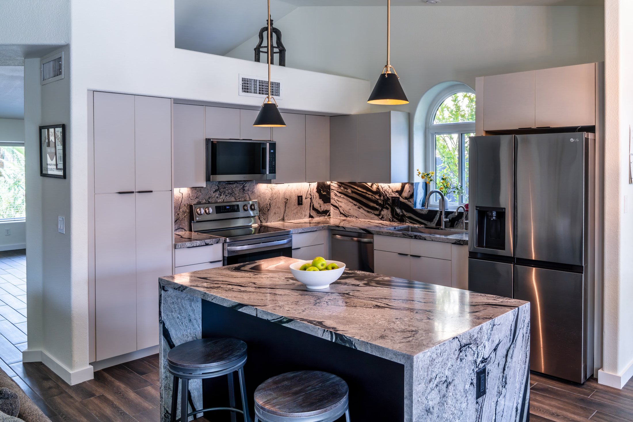 Open-concept Phoenix kitchen remodel with stone island, arched window and dining nook