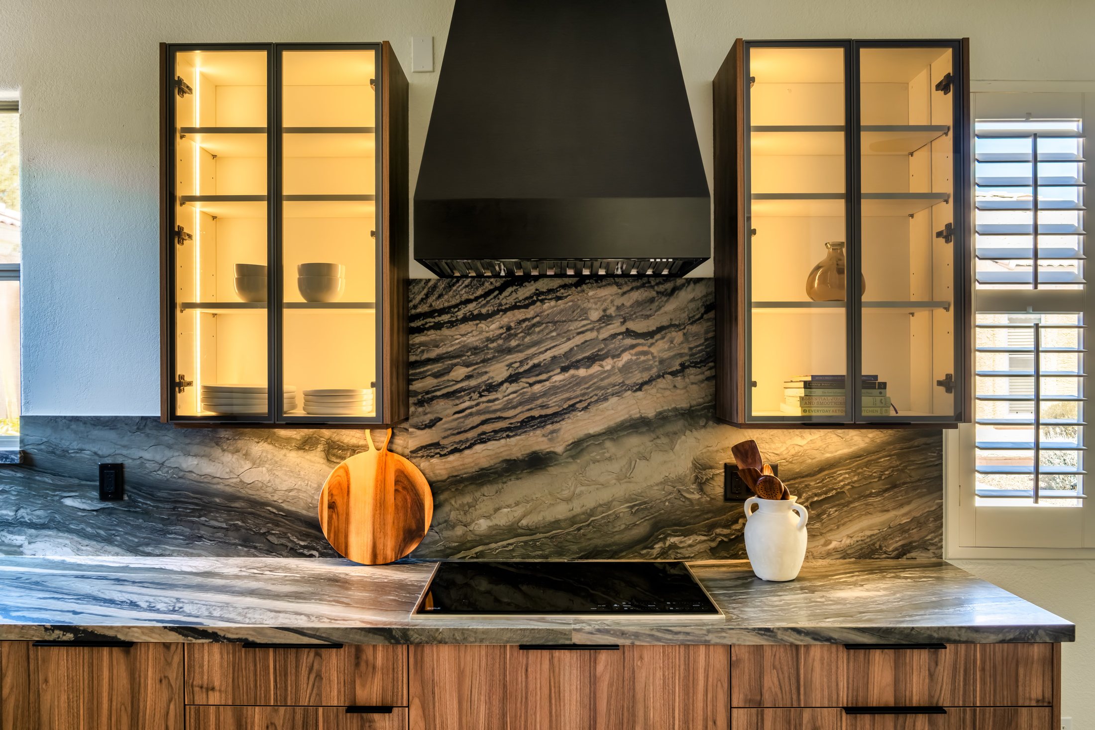 Phoenix kitchen remodel with walnut cabinetry, glass-front uppers and dramatic stone backsplash