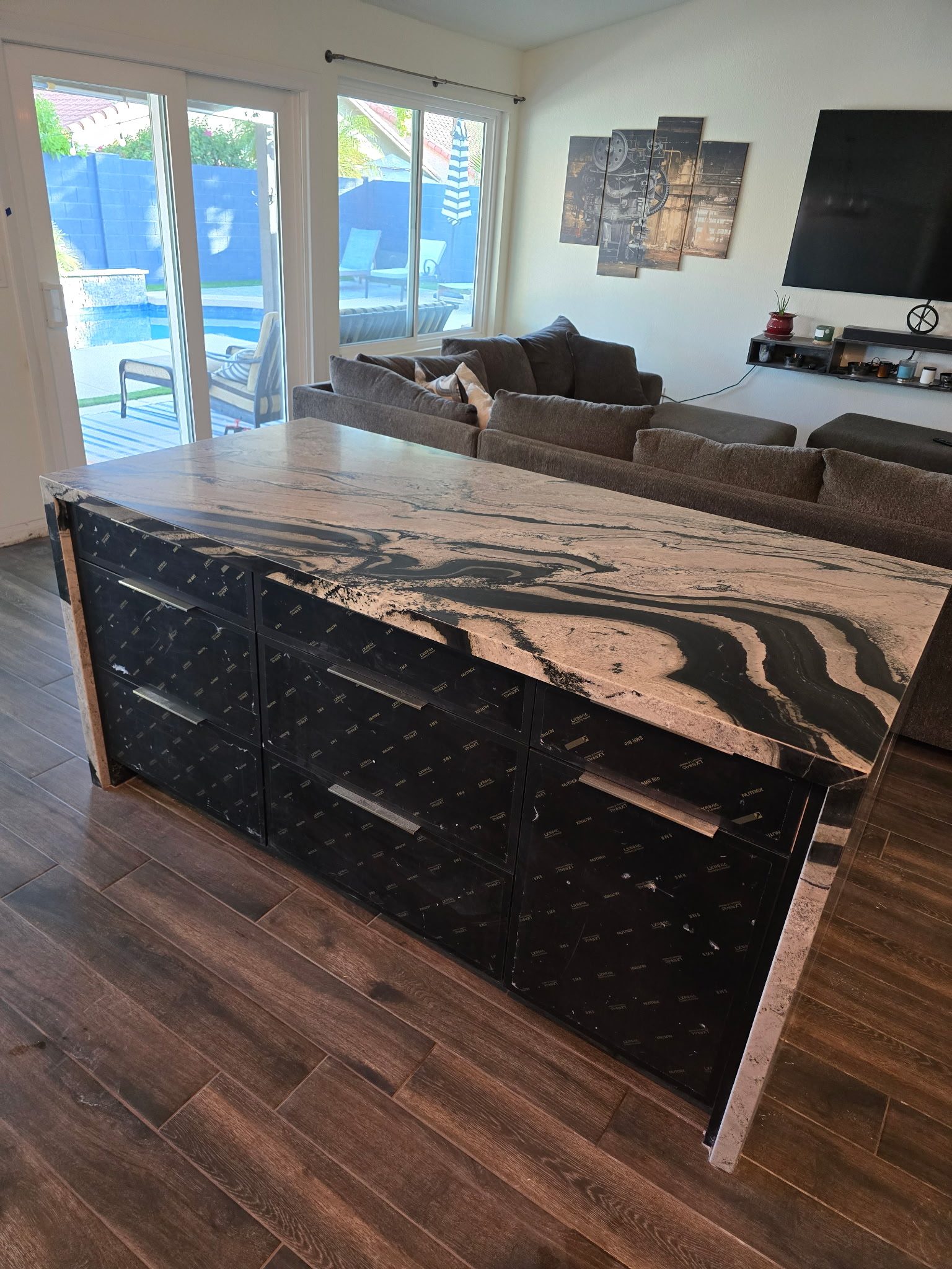 Waterfall stone island in a completed Phoenix kitchen remodel, open to the living room